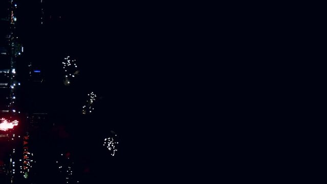 Fireworks display celebration for New year's eve with abstract multicolor big shining glowing fireworks show with bokeh lights in the night sky. Vertical Footage