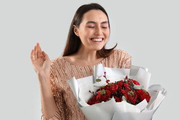 Young woman with bouquet of flowers on light background. Valentine's Day celebration