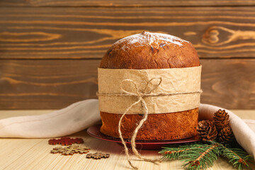 Panettone with fir branches, cones and snowflakes on wooden table