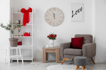 Interior of living room decorated for Valentine's Day with armchair, table and flowers