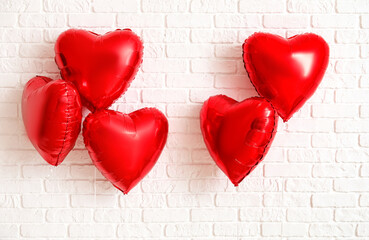 Heart shaped balloons for Valentine's Day on white brick background