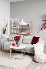 Interior of living room decorated for Valentine's Day with sofa, flowers and gifts