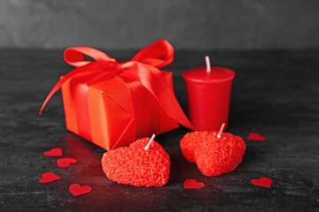 Beautiful candles, gift box and paper decor on dark background. Valentine's Day celebration