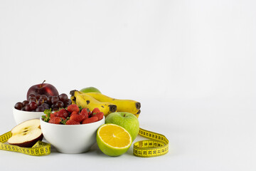 Set of juicy tropical fruits wrapped in a measuring tape, symbolizing healthy life, on white background