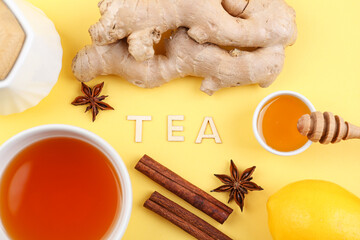 Ginger roots, cup of tea, cinnamon and anise on yellow background