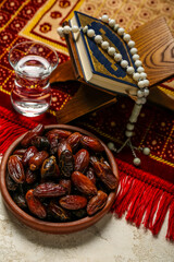 Dried dates, glass of water, Koran, prayer beads and mat for Ramadan on light background, closeup