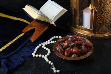 Dried dates, prayer beads, Koran and Muslim lantern for Ramadan on dark table
