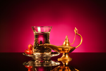 Aladdin lamp of wishes, glass and dates for Ramadan on table against dark red background