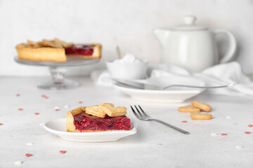 Heart-shaped plate with piece of sweet strawberry pie and cookie hearts for Valentine's day on white table