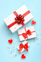 Gift boxes with beautiful bows and paper hearts on blue background. Valentine's Day celebration