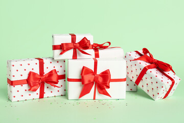 Obraz premium Gift boxes with beautiful bows on green background. Valentine's Day celebration