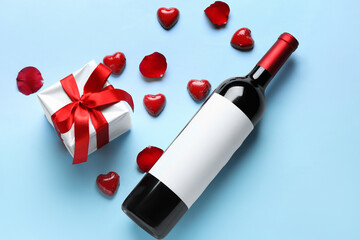 Bottle of wine, candies and gift on blue background. Valentine's Day celebration