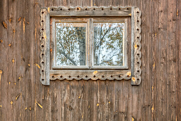 window with carved frame on weathered wooden wall of rural house