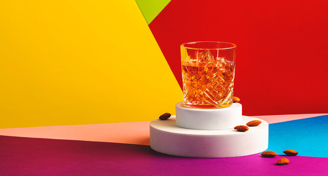 French connection alcoholic cocktail with cognac and amaretto liqueur. Modern style still life on fashionable multicolored background