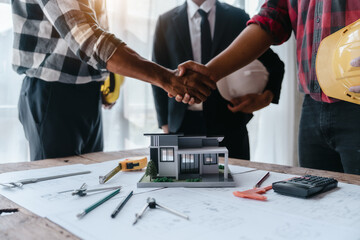 Shaking hands, Blueprints architects and building engineers talking meeting and planning will chronicle the design and technical aspects of a new house construction, renovation remodeling.