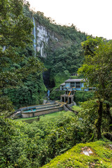vertical shot of hydroelectric plant in the middle of the tropical jungle with a waterfall in the background
