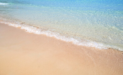 Fototapeta na wymiar Sand beach sea on sun light with sea wave.