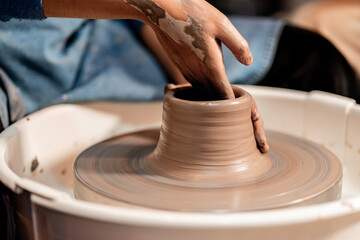 earthenware The art of sculpting clay with ceramics being molded by hand on a spinning machine. with the right posture to create a plate or vase professionally