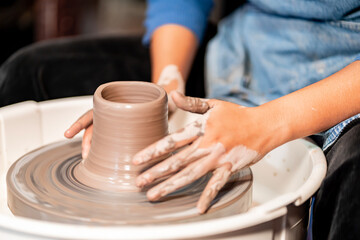 Fototapeta na wymiar earthenware The art of sculpting clay with ceramics being molded by hand on a spinning machine. with the right posture to create a plate or vase professionally