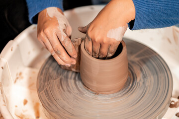 earthenware The art of sculpting clay with ceramics being molded by hand on a spinning machine. with the right posture to create a plate or vase professionally