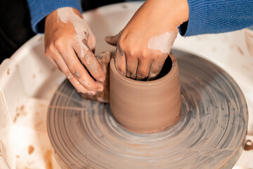earthenware The art of sculpting clay with ceramics being molded by hand on a spinning machine. with the right posture to create a plate or vase professionally