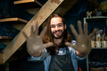 Obraz na płótnie Canvas male artist making pottery in workshop. male artist making pottery in workshop. show his hands with mud 