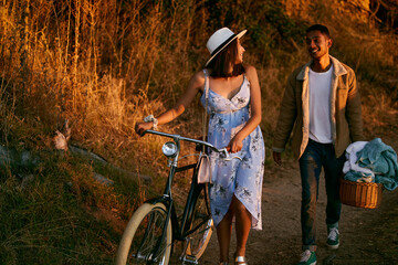 Romantic, happy and couple on a picnic in a park for a date, holiday and love in Indonesia. Travel, smile and man and woman walking in nature for romance, peace and relax with food during sunset
