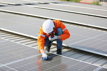 A worker is fixing solar panels on the roof. Engineer and technician using laptop checking and operating solar panels system on rooftop of solar cell farm power plant, Renewable energy source.