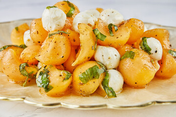 Salad with melon mugs baby mozzarella and herbs on white marble