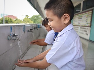Elementary students wash their hands in the sinks in the school
