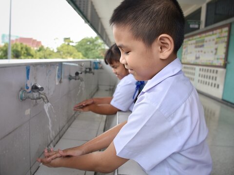 Elementary students wash their hands in the sinks in the school