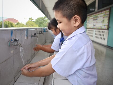 Elementary students wash their hands in the sinks in the school