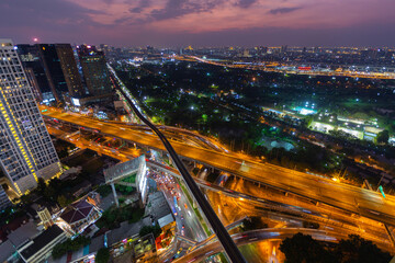 Aerial view of Lat Phrao road intersection with traffic jams on the city skyline at dusk.