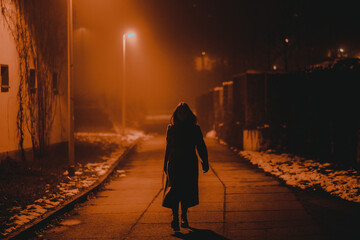 silhouette of a young woman in a foggy night winter city - 562634474