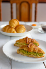 Croissant sandwich with egg,avocado on white dish and honey, coffee. breakfast and healthy food concept.