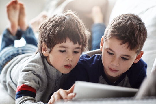 Children, bonding or tablet for movies streaming, brothers esports or social media on relax house sofa or home living room. Thinking, curious or kids on digital technology in education team learning