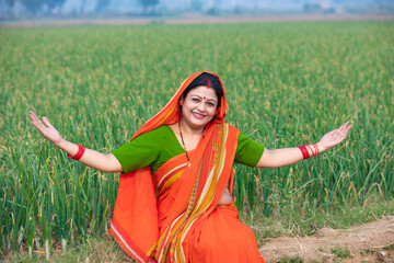 Indian rural woman spreading hand and giving expression at agriculture field.