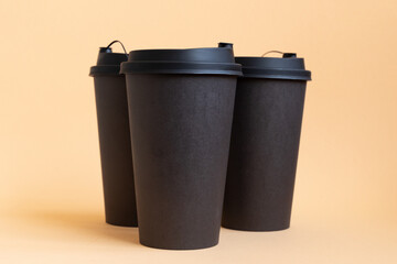 Set of three takeaway black coffee cup on neutral background natural light. Mock -up, nobody, front view