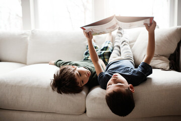 Reading, learning and children with books on the sofa for knowledge, information and education. Relax, content and boys with a story for happiness, studying and playing on the living room couch