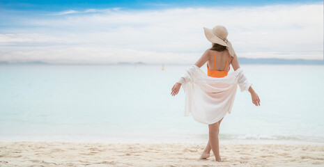 Asian tourist woman in orange bikini on the beach