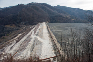 Barrier stopping the flow of copper and gold mining mining residuals into a settling basin,...