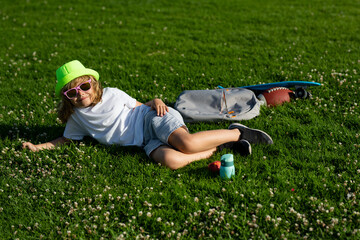 Kid relaxing on green meadow. Child playing in garden. Happy little boy lying on the grass at the spring day.