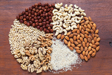 Close-up view of set tasty nuts: walnuts, pine nuts, sesame, hazelnuts, cashews, almonds on wooden background. Organic vegetarian healthy food. Edible background. Flat lay, mockup, top view