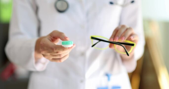 Doctor ophthalmologist holding eyeglasses and contact lenses in hands closeup 4k movie slow motion 