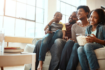 Happy black family on sofa for movie, television or film together, bonding and quality time in living room. Popcorn, kids TV show and people, mother and father with kids, sitting on couch watching