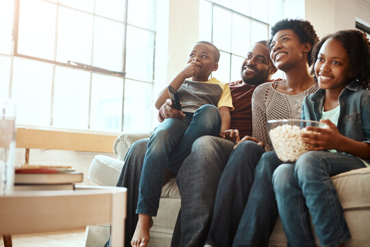 Happy Black Family On Sofa For Movie, Television Or Film Together, Bonding And Quality Time In Living Room. Popcorn, Kids TV Show And People, Mother And Father With Kids, Sitting On Couch Watching