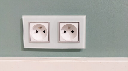 white electric outlet french model mounted on green wall