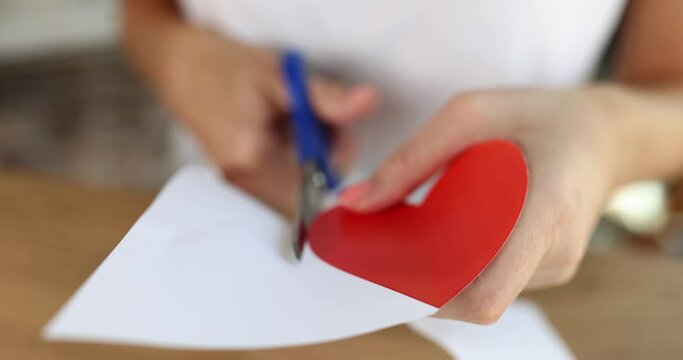 Woman cutting out of paper red heart with scissors closeup 4k movie slow motion 