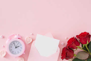 Women day concept. Top view photo of open envelope with white card, red flowers, alarm clock and...