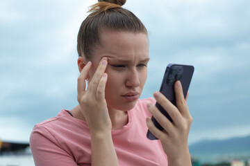 Girl with vision problems tries to read text on the phone. Bad vision concept. Woman looking at the...